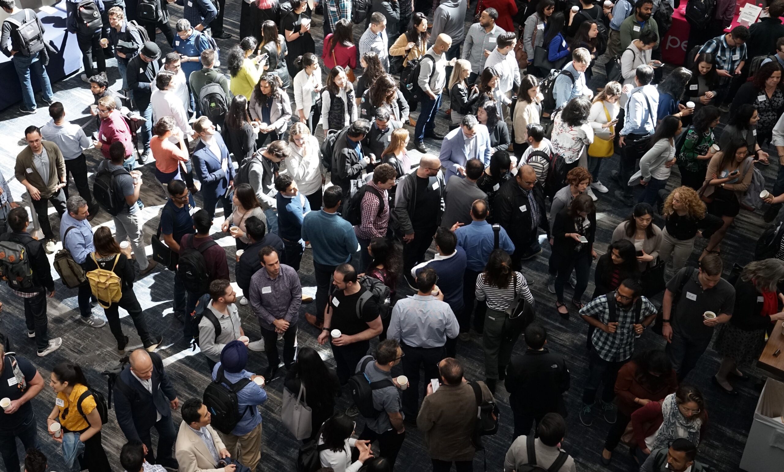 A photograph of a large group of people lingering and chatting at an event.