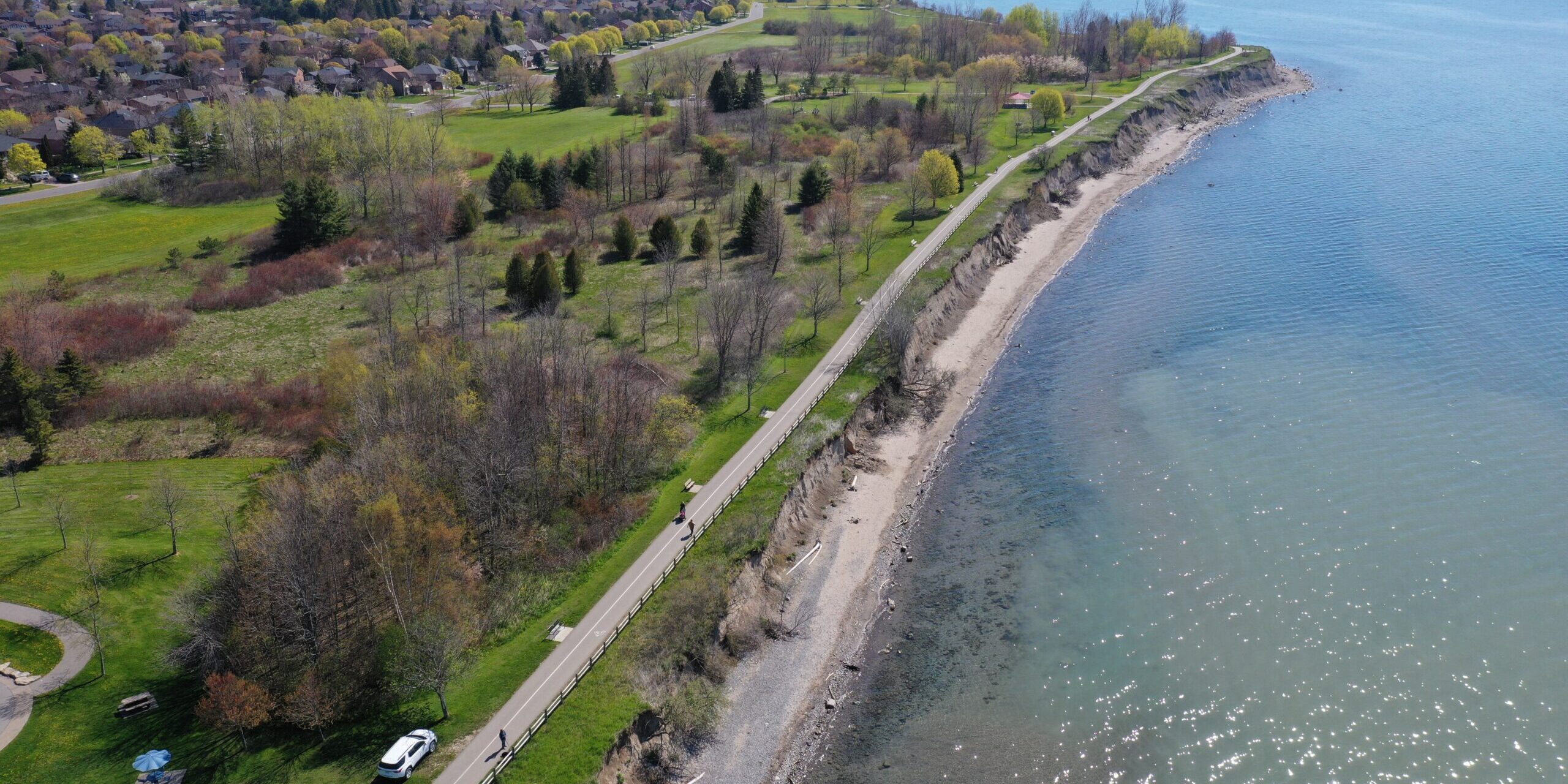 Drone photo of Ajax Waterfront Park facing west the area between Lake Driveway W and Lake Ontario with park, bluffs and beach.