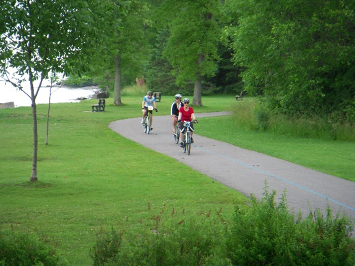 Three cyclists riding along a paved multi-use trail